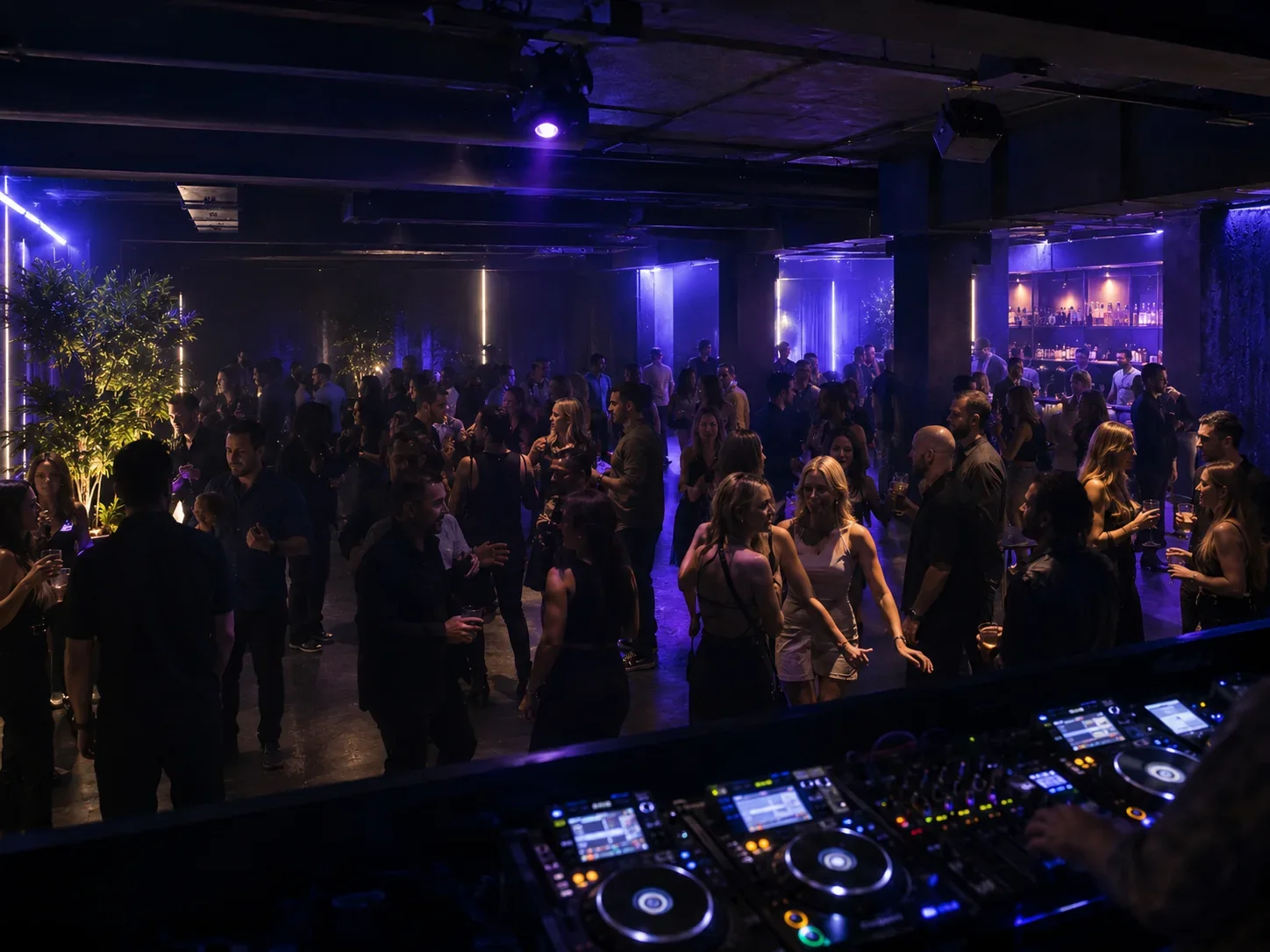 Ausgelassene Clubnacht mit voller Tanzfläche, DJ-Pult und violetter Lichtstimmung.