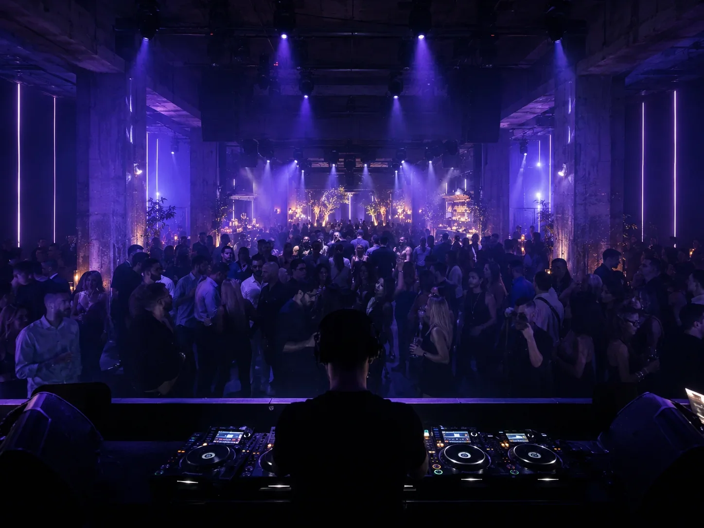 DJ mit Blick auf die dicht gefüllte Tanzfläche während einer energiegeladenen Clubnacht.